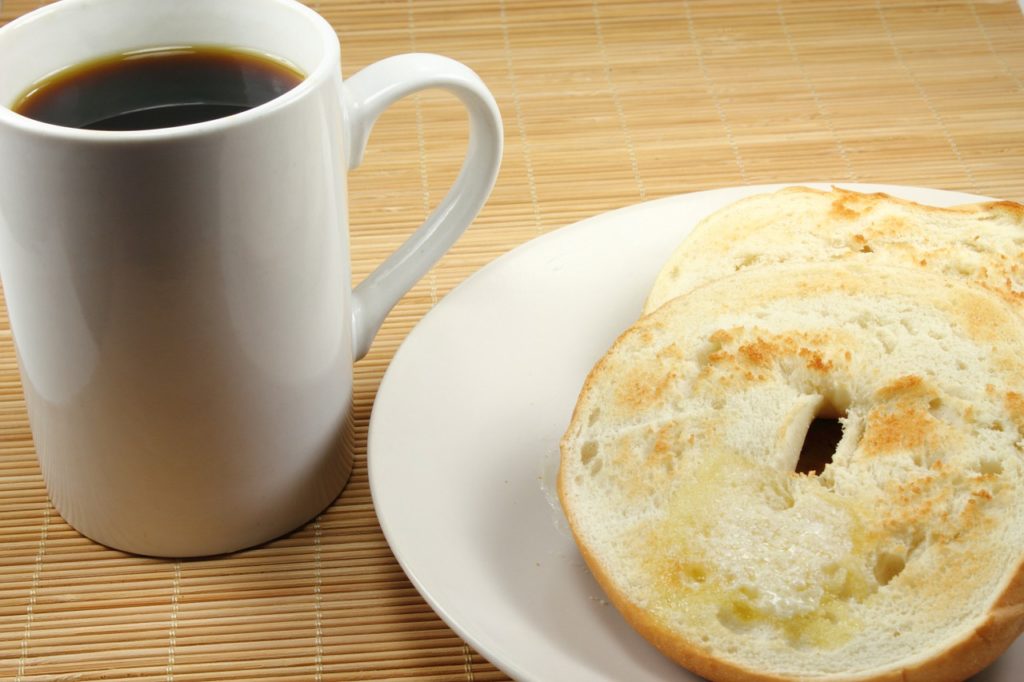 Plain bagel on a plate with a mug of coffee